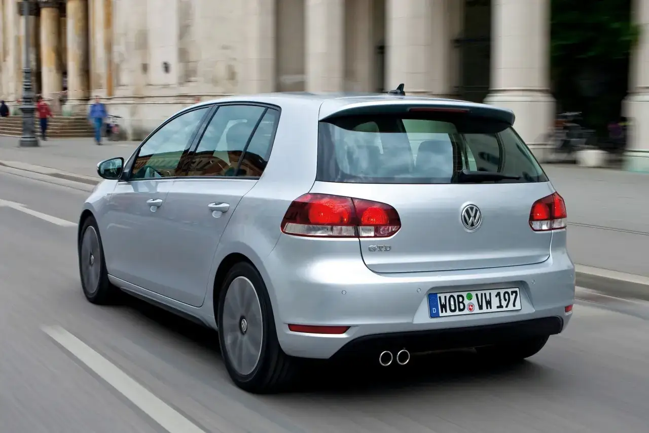 Srebrny Golf 6 R w ruchu miejskim, z widocznymi podwójnymi końcówkami wydechu i charakterystycznym znaczkiem GTD.