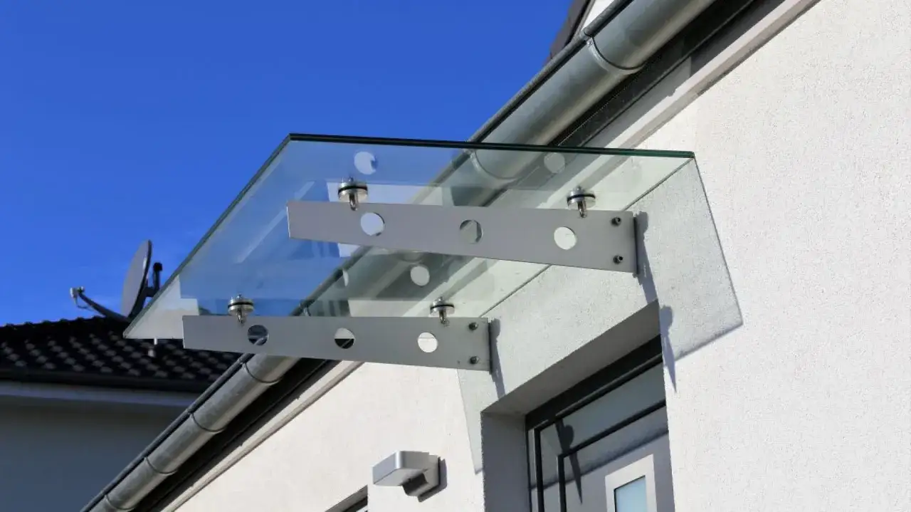 Nowoczesny szklany daszek nad drzwiami, idealny przykład jak zrobić daszek nad drzwi.