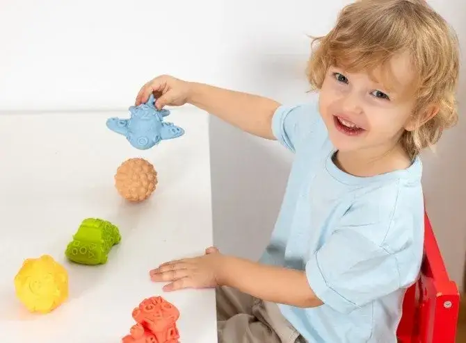 dziecko bawiące się piłkami sensorycznymi Tullo