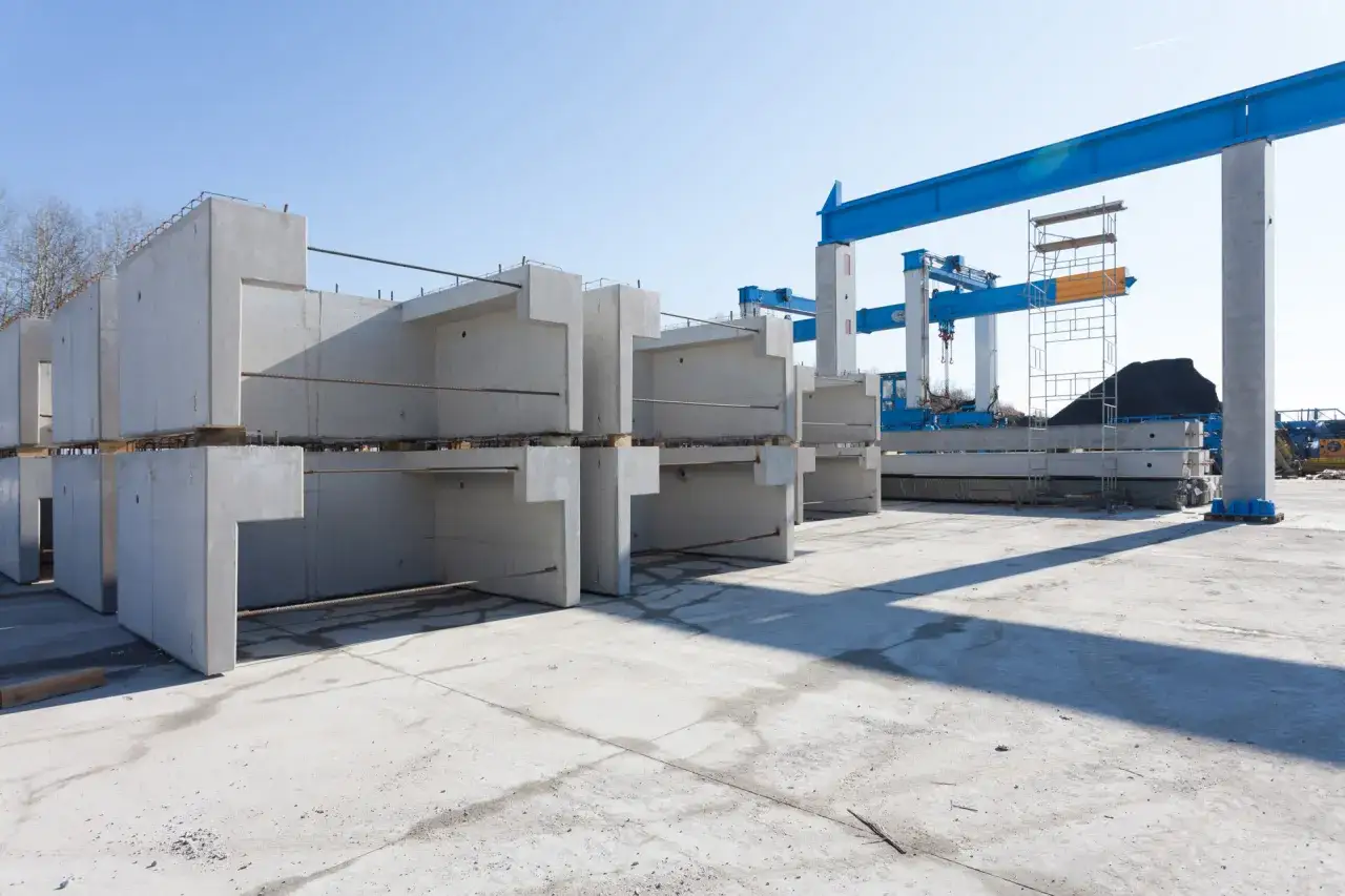 Betonowe elementy konstrukcyjne czekają na transport. Doki przeładunkowe i suwnice gotowe do pracy.