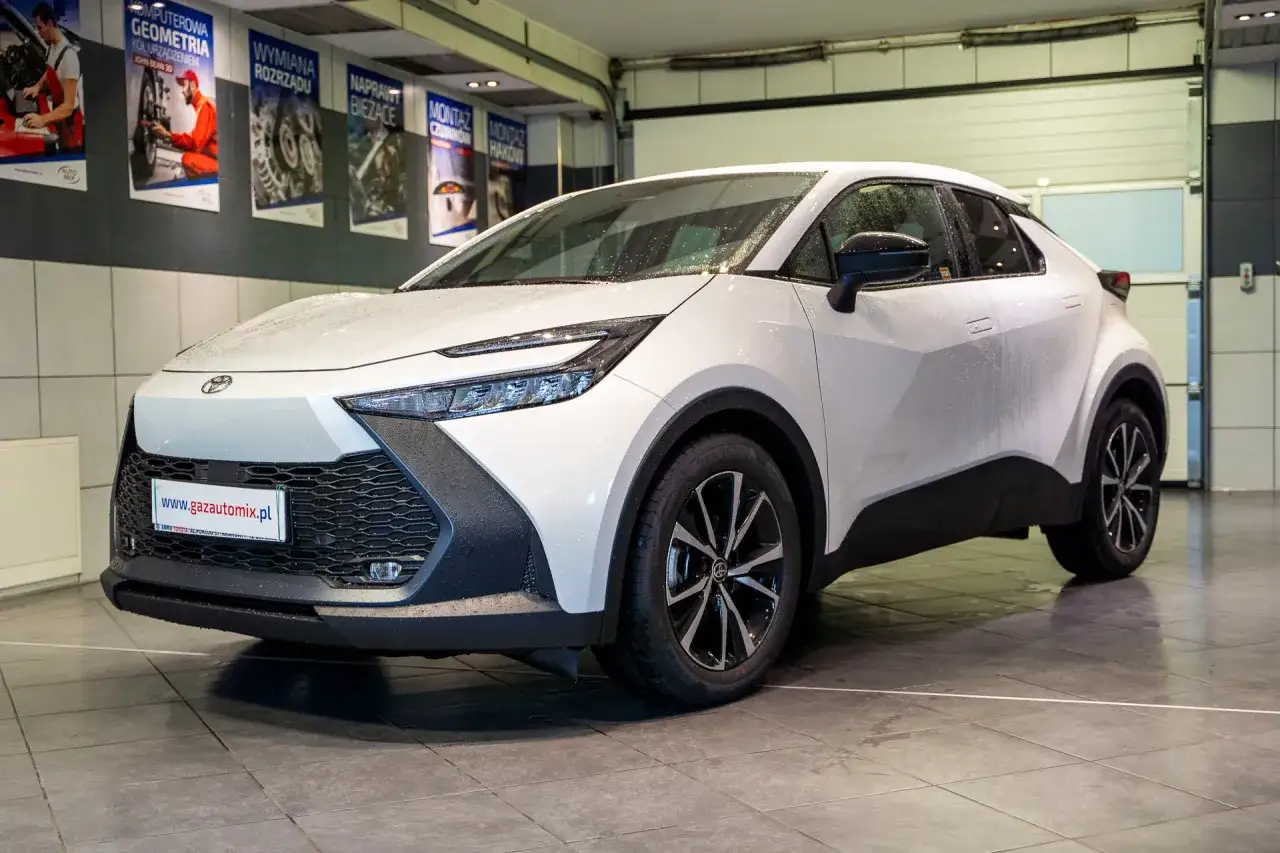 Biała Toyota C-HR po montażu LPG bez utraty gwarancji. Auto stoi w serwisie, na podłodze widać krople wody.