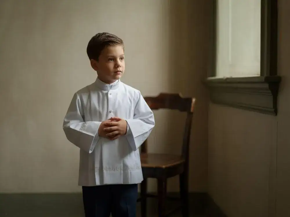 chłopiec w białej koszuli i eleganckich spodniach pod albę komunijną
