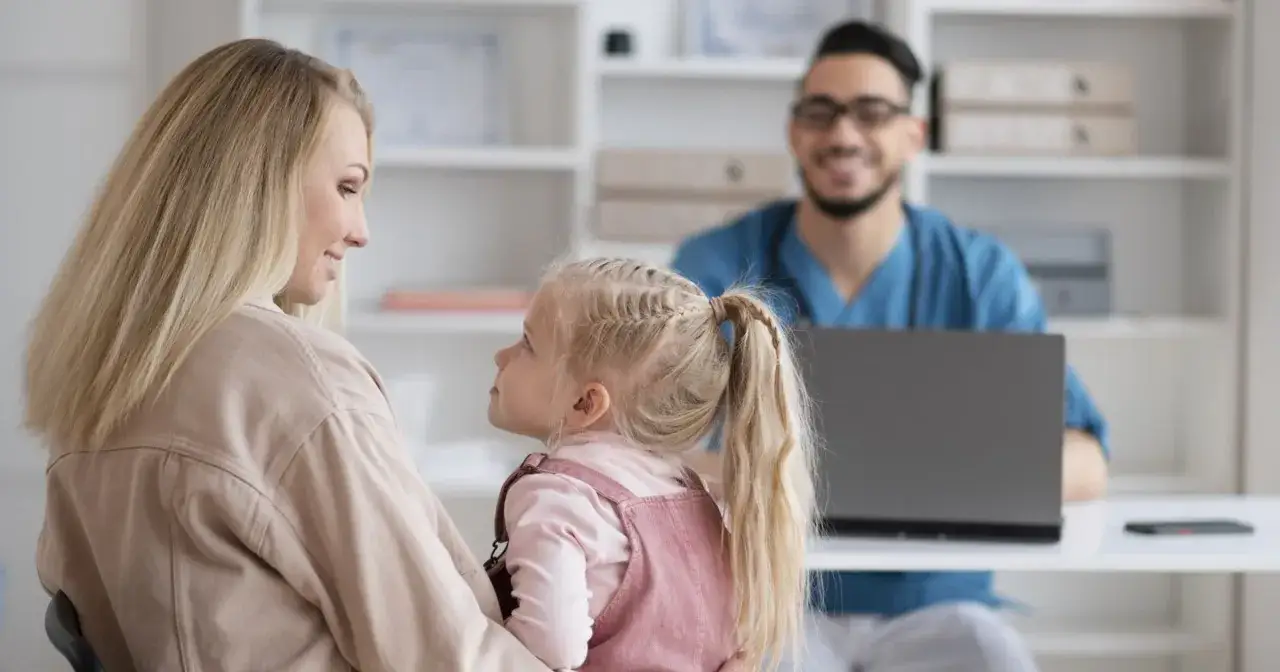 Mama z córką w gabinecie lekarskim. Dowiedz się, jak zarejestrować się do lekarza przez internet, by uniknąć kolejek.