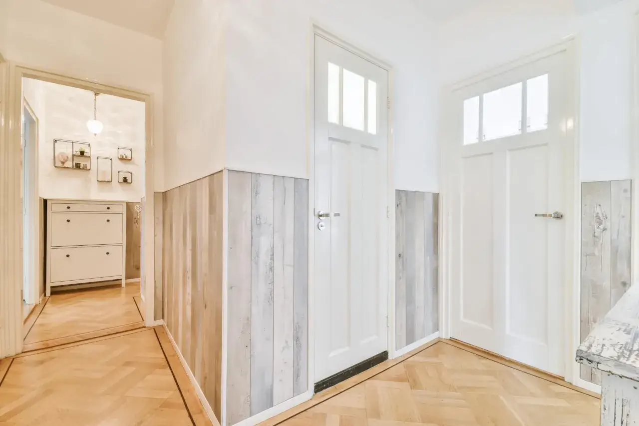 Stara boazeria w nowej odsłonie – panele imitujące drewno nadają korytarzowi nowoczesny charakter.