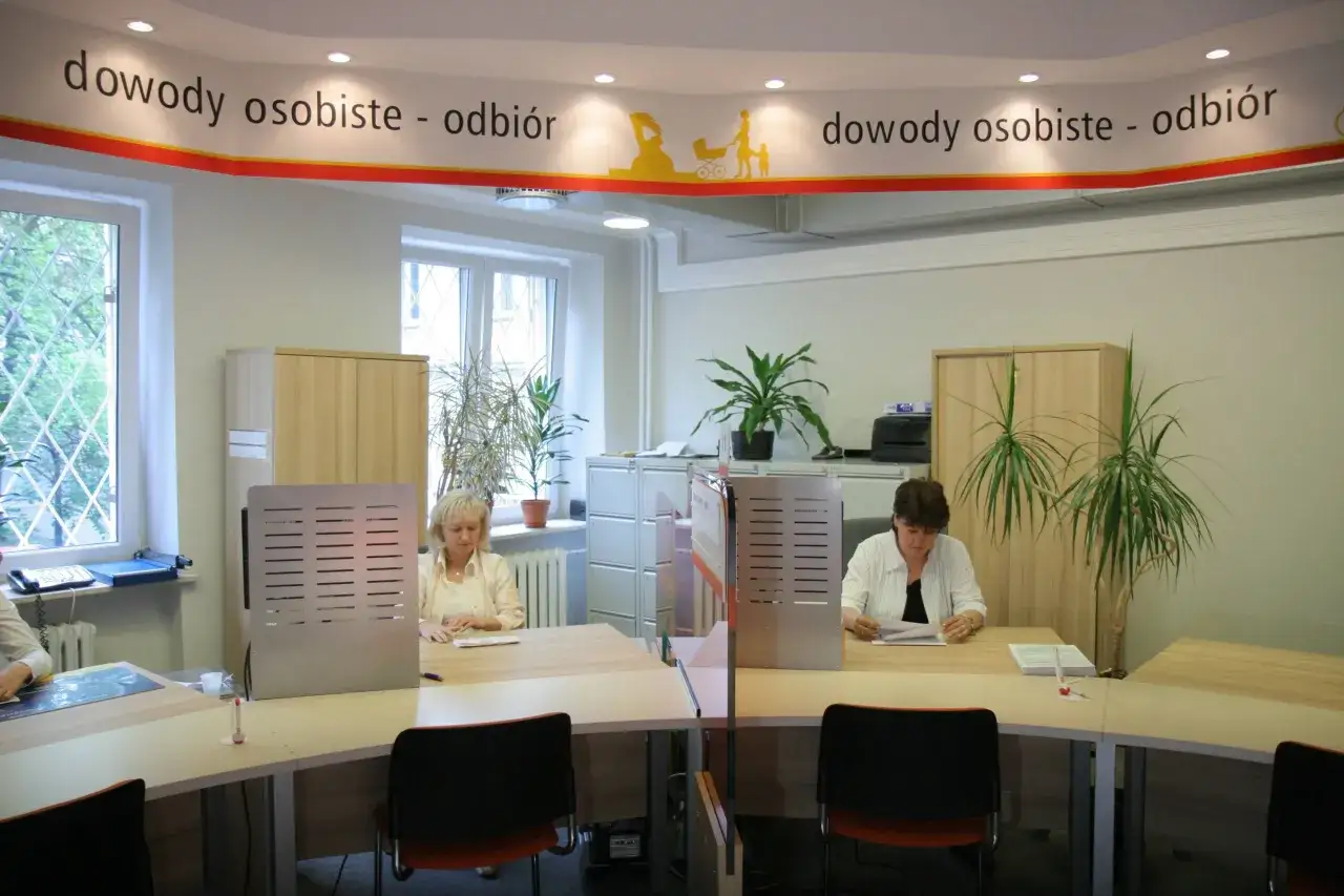 Urząd, gdzie wydawane są dowody osobiste. Pracownice obsługują klientów przy biurkach. To miejsce, gdzie załatwia się sprawy urzędowe, czyli budżetówka.