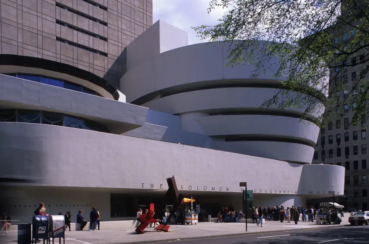Muzeum Guggenheima w Nowym Jorku, z jego charakterystyczną spiralną architekturą, prezentuje dzieła sztuki na tle miejskiego krajobrazu.