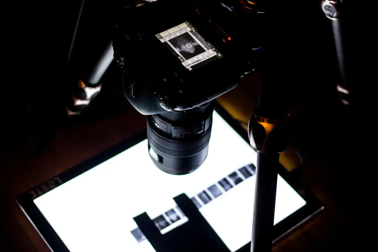Analogowa fotografia w akcji: aparat na statywie skanuje kliszę na podświetlanej płycie.