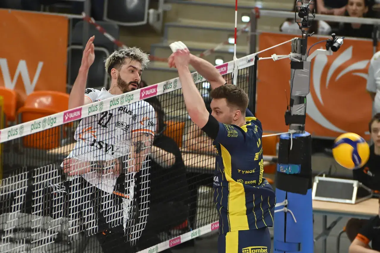 Siatkarze walczą przy siatce w Plus Lidze. Jeden z nich próbuje zablokować atak, drugi szykuje się do przyjęcia. To emocje, które często towarzyszą plus liga transfery.