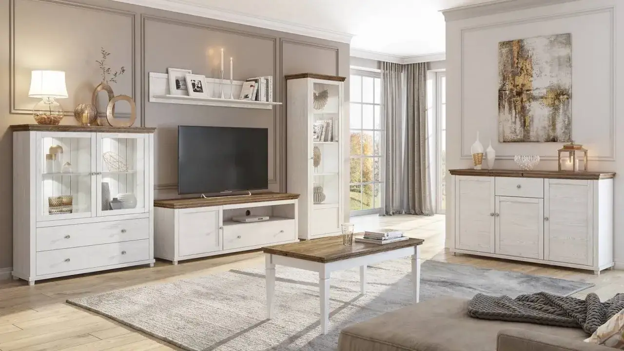 Salon w stylu prowansalskim: białe meble z drewnianymi blatami, komoda, witryna, szafka RTV, stolik kawowy, dywan i obraz.