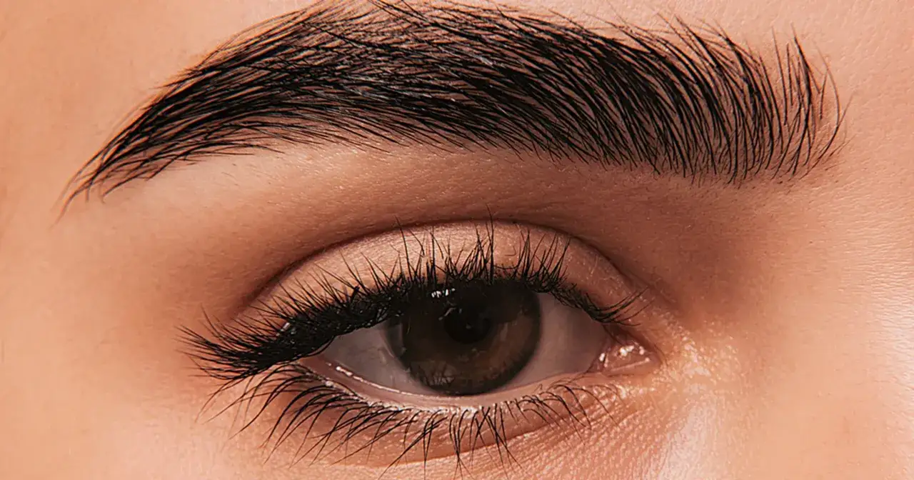 Odkryj co na porost rzęs domowe sposoby! Zbliżenie na oko z gęstymi, ciemnymi rzęsami i podkreślonymi brwiami.