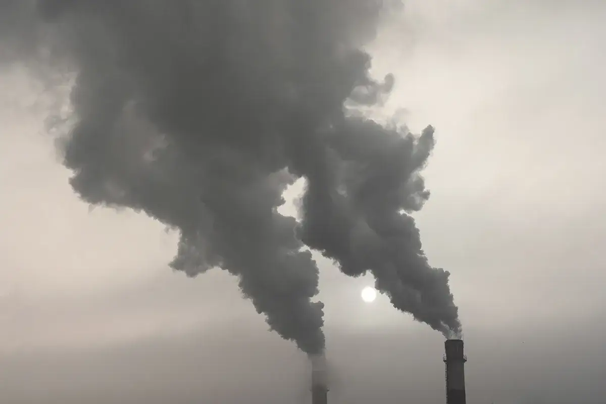 Dymiące kominy fabryczne, wypuszczające ciemne kłęby, które zasłaniają słońce. To właśnie takie emisje tworzą pył PM10, co to jest?