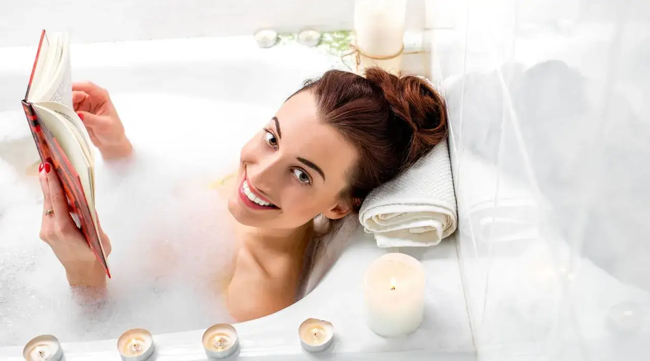 Kobieta czyta książkę w wannie pełnej piany. To idealna gorąca kąpiel na przeziębienie, relaksująca i kojąca.