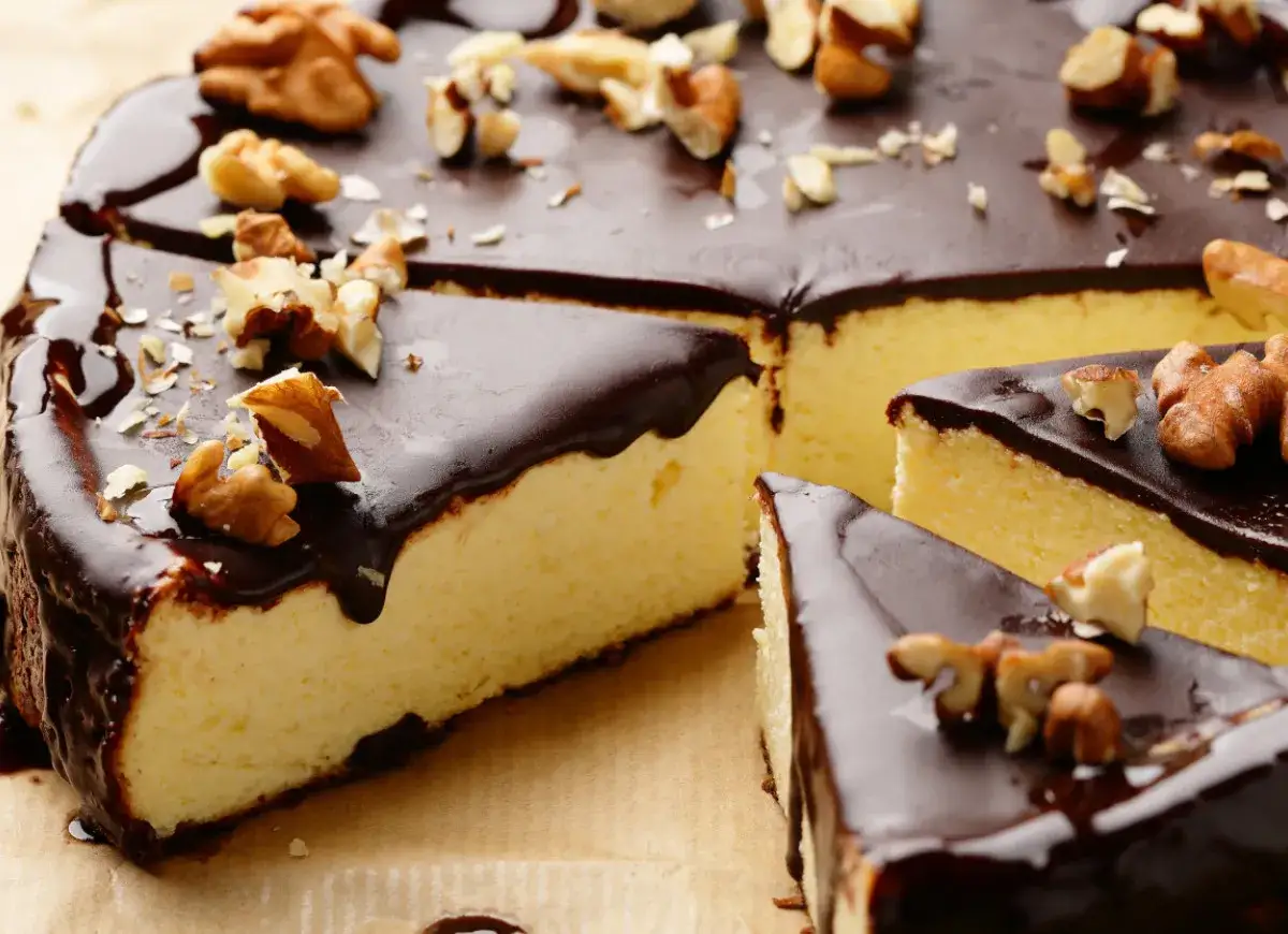 Pyszny sernik z polewą czekoladową i orzechami. Idealny moment, kiedy polać ciasto polewą czekoladową, by wyglądało tak apetycznie.