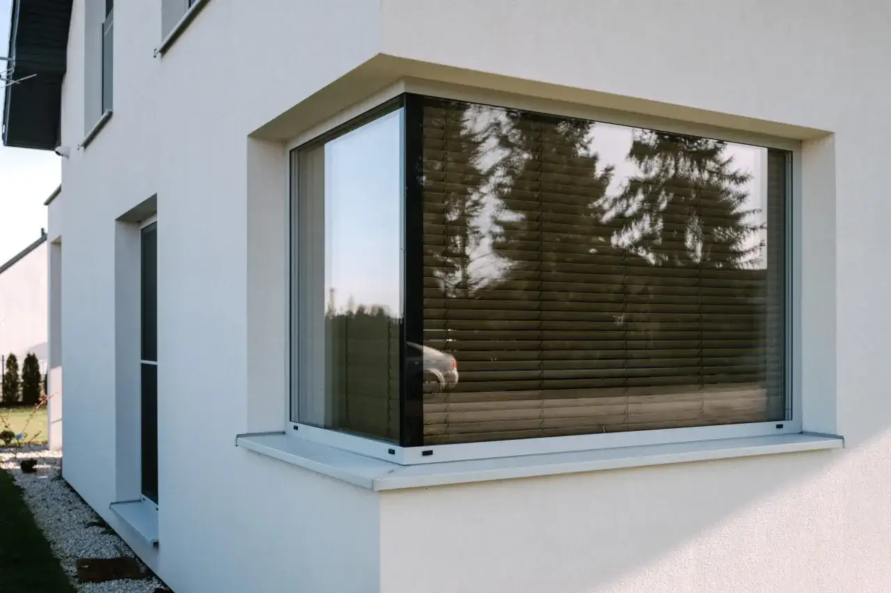 Nowoczesny narożny okno z żaluzjami, pokazujące różne sposoby otwierania okien i zapewniające prywatność.