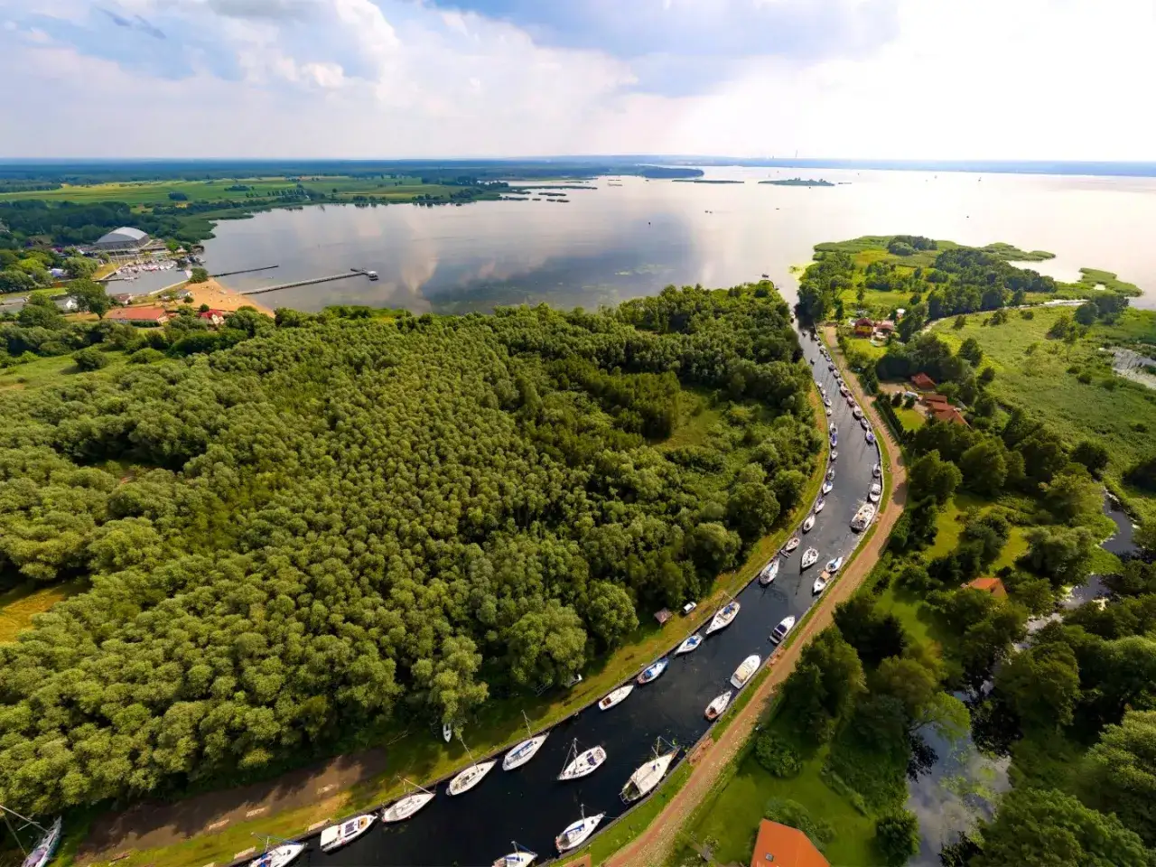 Malowniczy widok na jezioro i kanał z łodziami. Czy Polska ma jakieś wyspy? Tak, a ten krajobraz przypomina te z Mazur.
