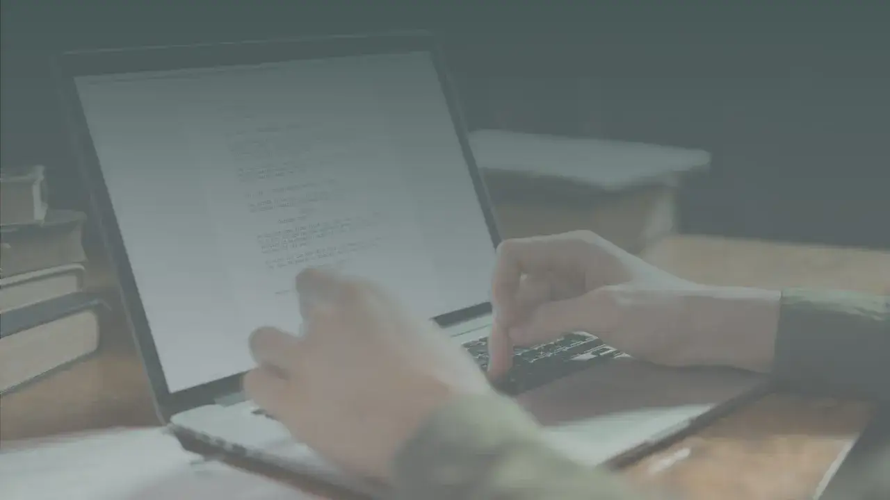 Ręce piszą scenariusz na laptopie, pokazując, jak napisać książkę. Obok stos książek.
