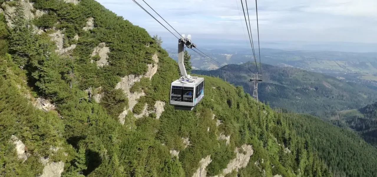Kolejka linowa wjeżdża na zbocze porośnięte kosodrzewiną, w tle rozciąga się widok na Tatry. Pkl Kasprowy Wierch.