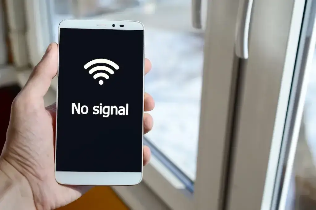 Osoba trzymająca telefon z ikoną braku zasięgu