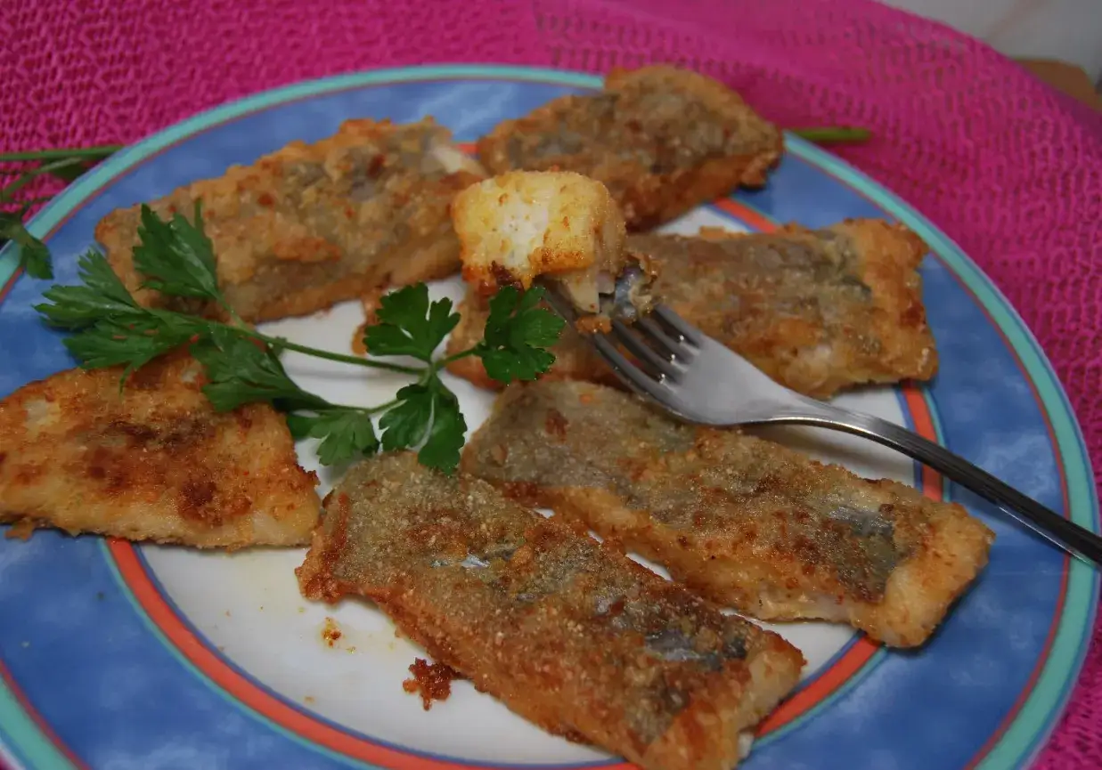 Usmażona miruna na talerzu z cytryną i natką pietruszki