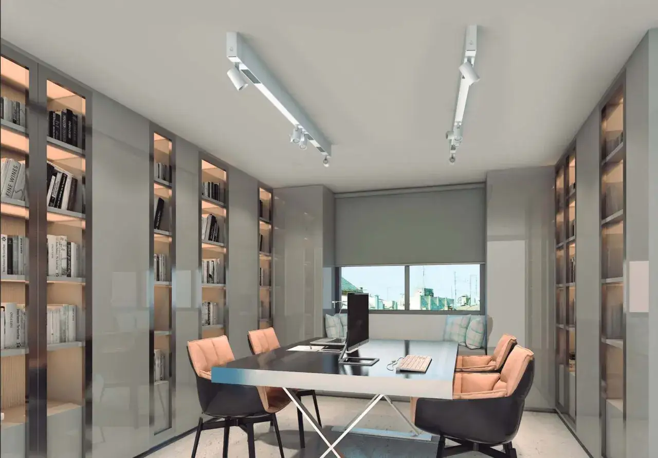 Nowoczesne biuro z regałami pełnymi książek i dwoma systemami szynowymi z reflektorami. To właśnie **led zintegrowany co to znaczy** &ndash; światło idealnie dopasowane do przestrzeni.