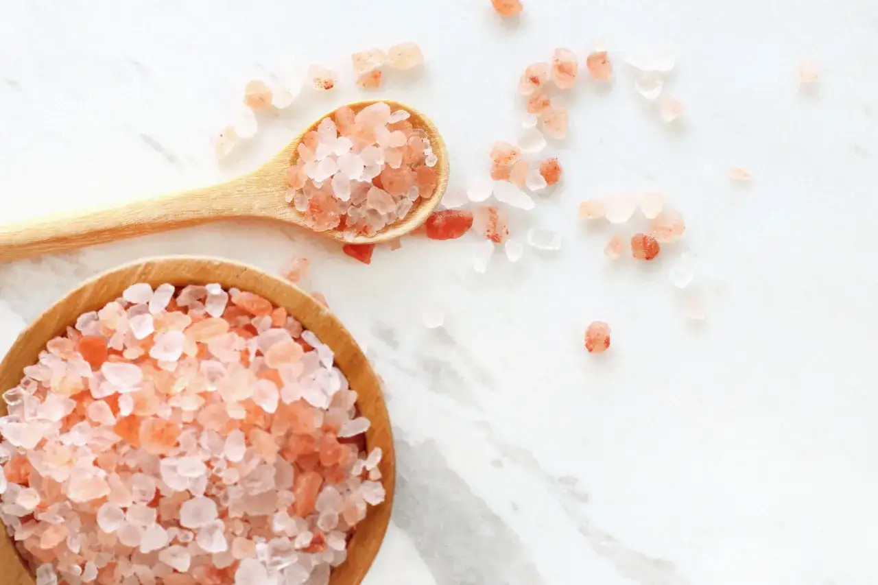 Różowa sól himalajska w drewnianej miseczce i łyżce. Ile soli dziennie dla sportowców? To pytanie o zdrowie i wydolność.