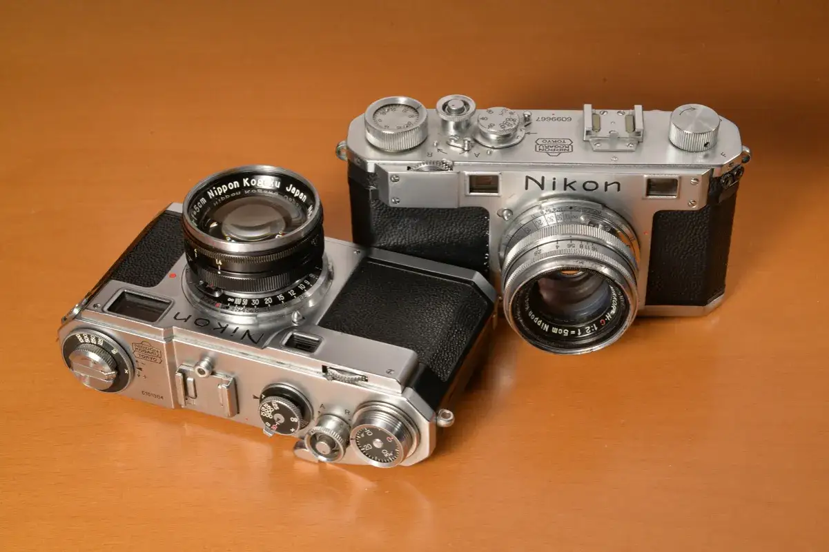 Dwa klasyczne nikon modele po kolei: jeden z obiektywem 50mm, drugi z szerszym.