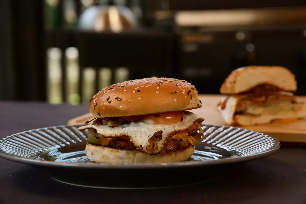 Pyszny domowy hamburger z jajkiem sadzonym, serem i piklami. Idealny przepis na to, jak zrobić domowego hamburgera.