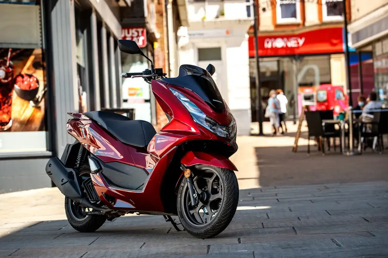 Błyszczący, czerwony skuter Honda PCX 125 na ulicy. Idealny do miasta, z niskim spalaniem.