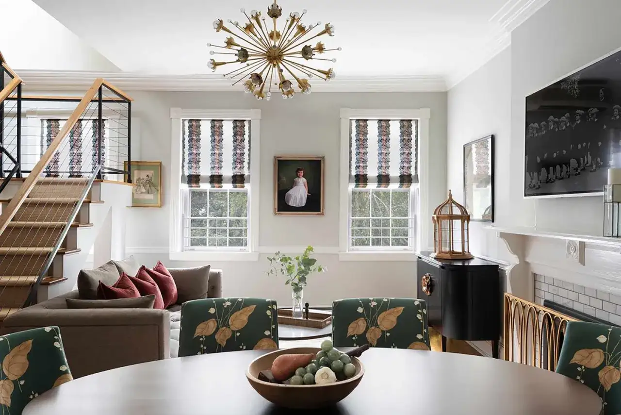 Oświetlenie salonu inspiracje: złoty żyrandol nad stołem, schody, kanapa i stylowe krzesła.