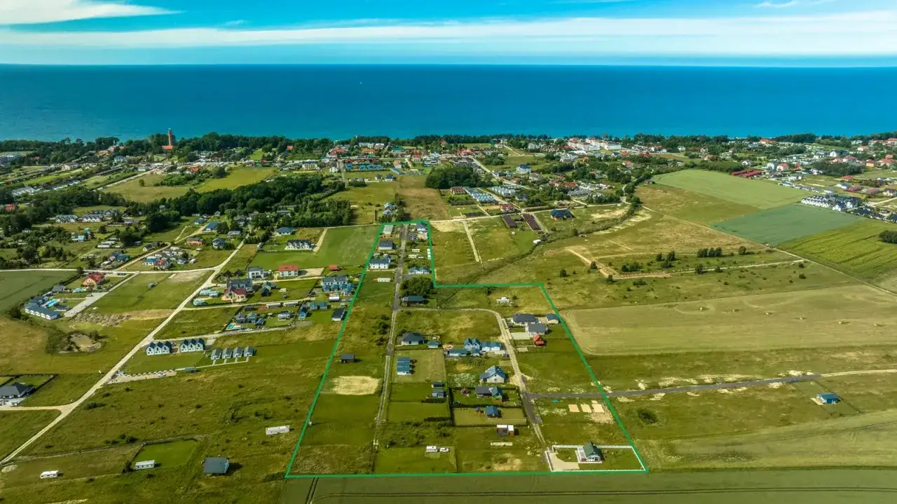 Działka z widokiem na morze, otoczona zielenią i domkami jednorodzinnymi. Idealne miejsce na wymarzony dom blisko plaży.