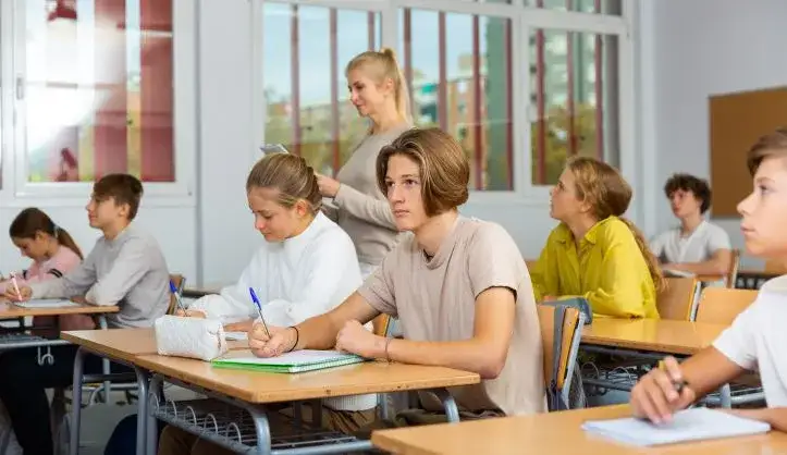 nauczyciel obserwujący ucznia w klasie notatki