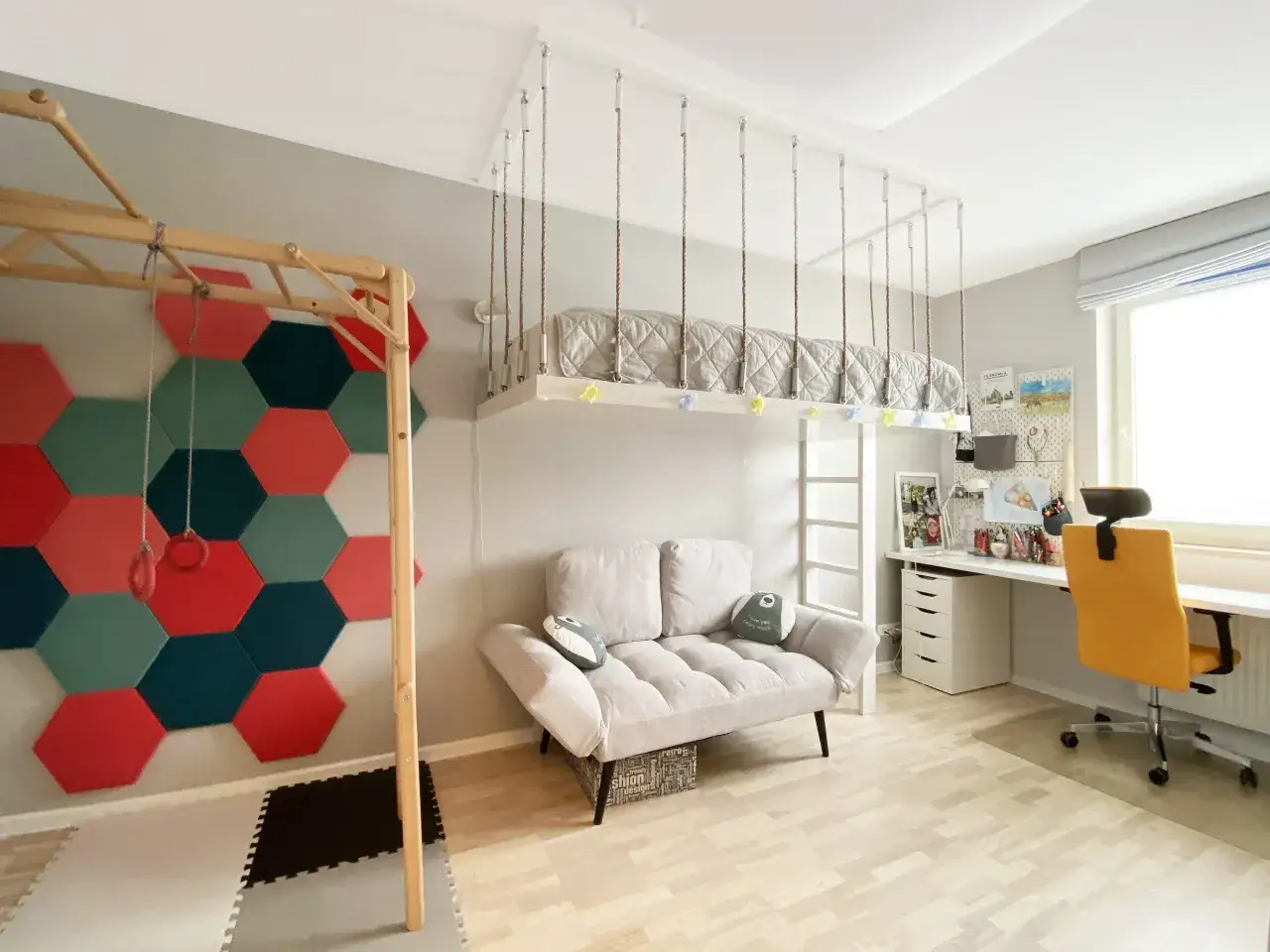Pokój dla 2 nastolatków aranżacje: łóżko zawieszone pod sufitem, kanapa, drabinka gimnastyczna i biurko.