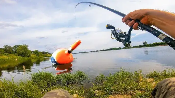 Wędkarz nad rzeką z wędką i spławikiem