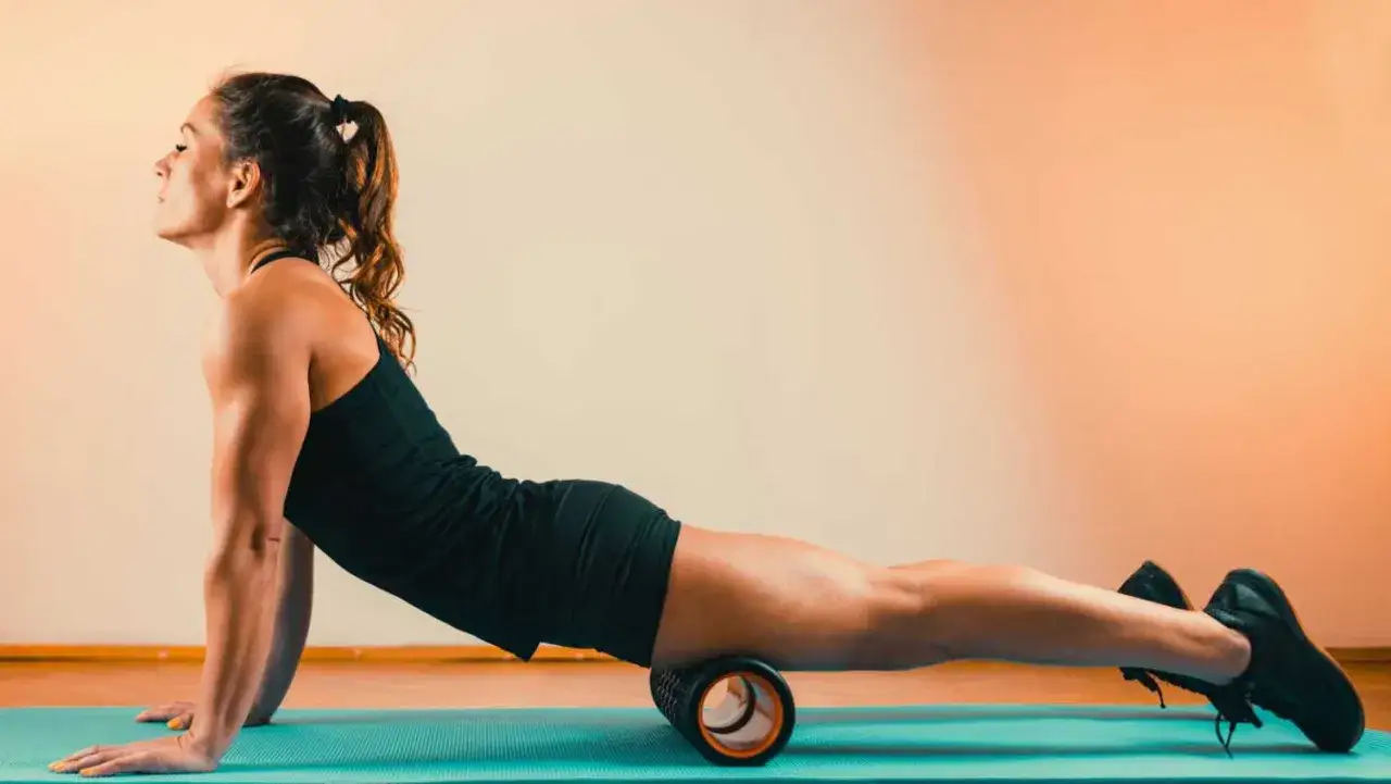 osoba rolująca mięśnie wałkiem piankowym