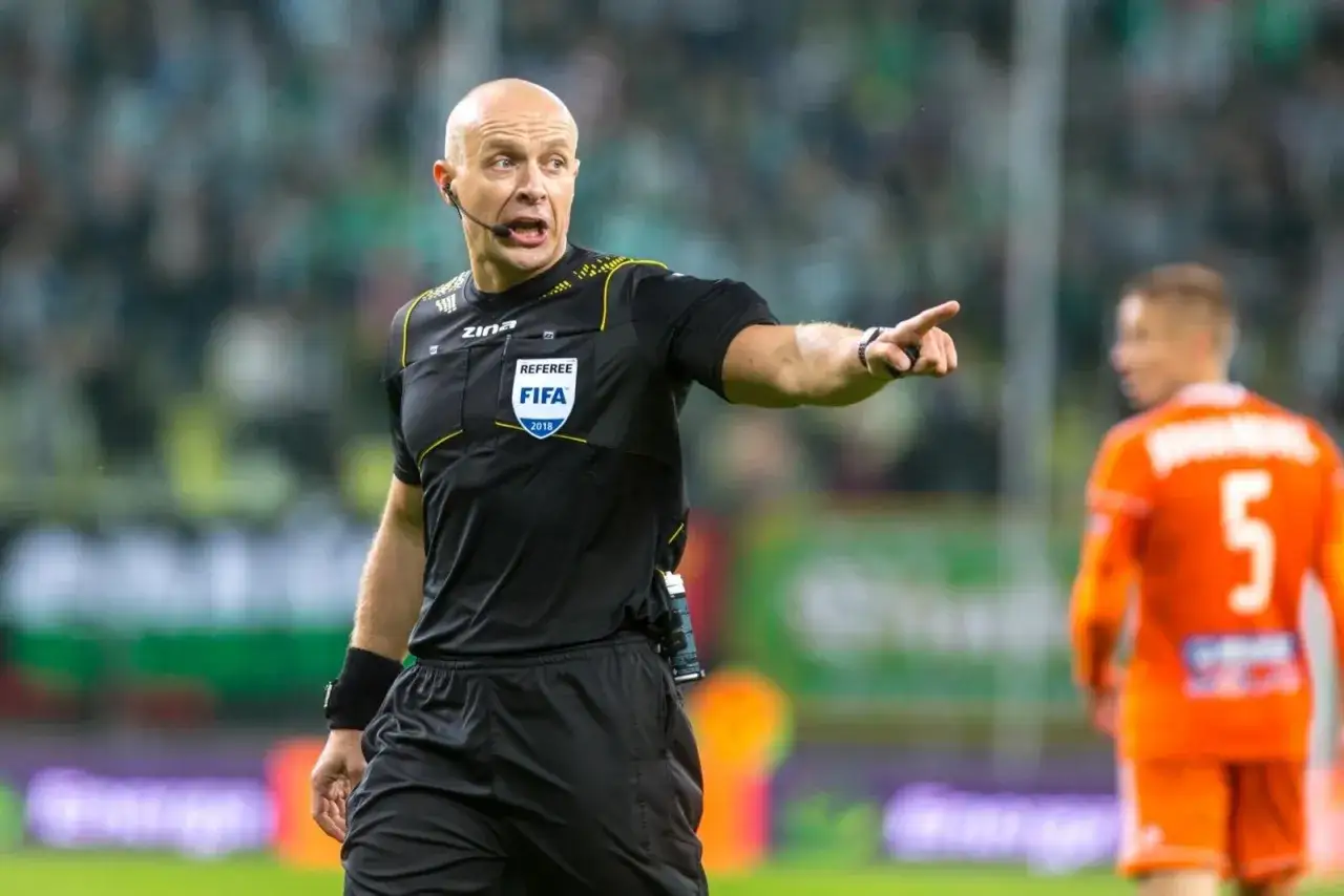 Sędzia FIFA na boisku, wskazujący palcem. Ciekawe, ile zarabia sędzia ekstraklasy za takie emocje.