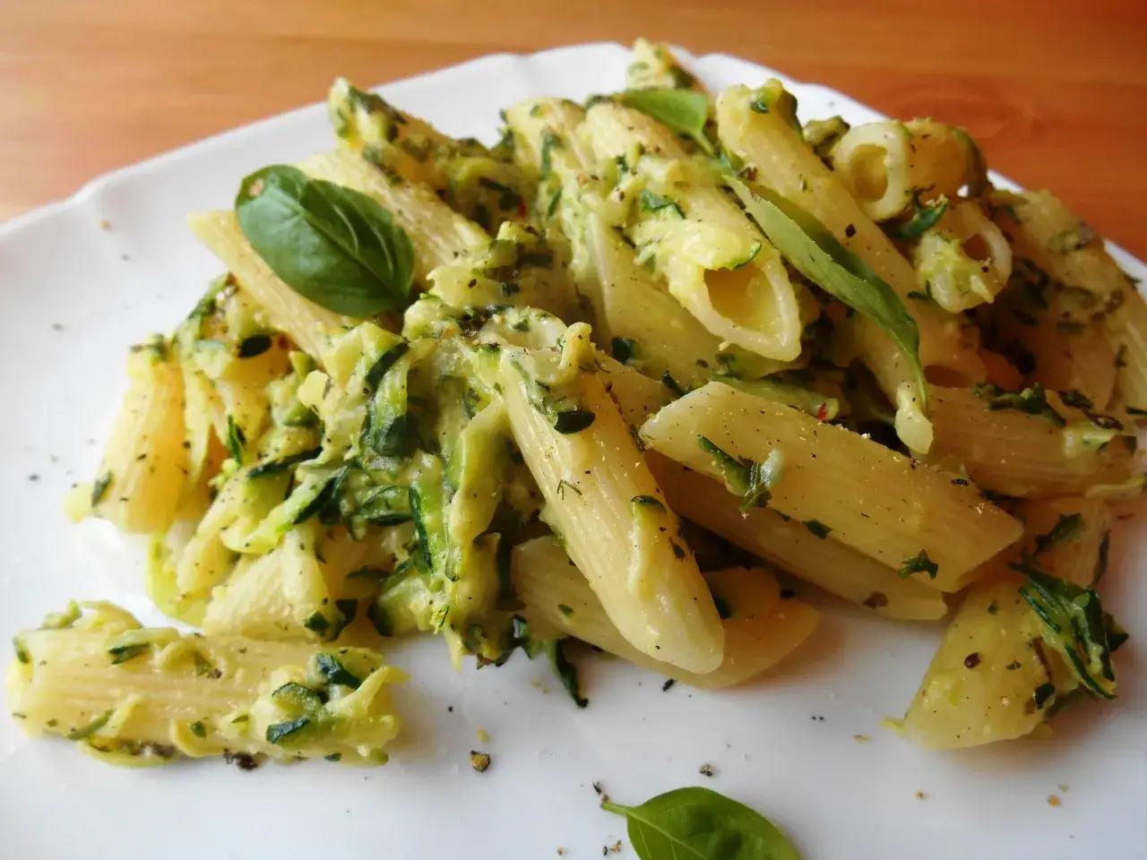 Penne z cukinią w kremowym sosie, udekorowane listkami bazylii. Pyszne danie, kt&oacute;re zachwyci każdego miłośnika makaronu.