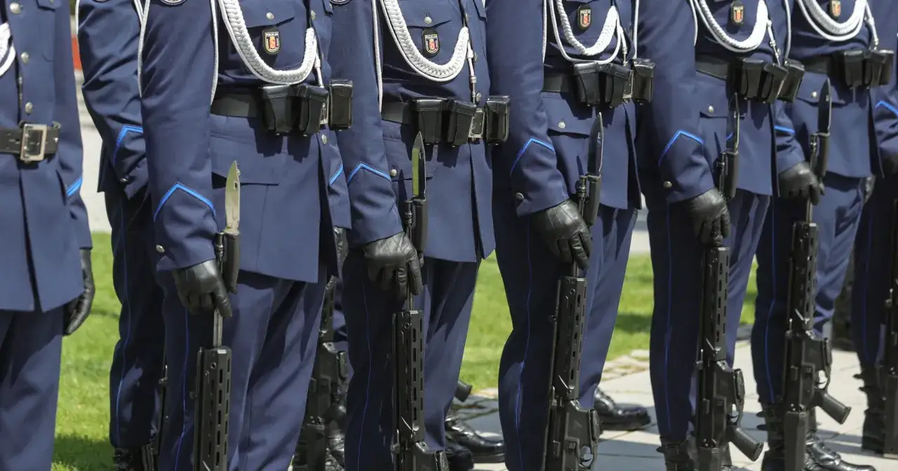 Policjanci w granatowych mundurach, z karabinami i bagnetami, stoją w szeregu. Czy mundurowi płacą ZUS? To pytanie, które często nurtuje obywateli.