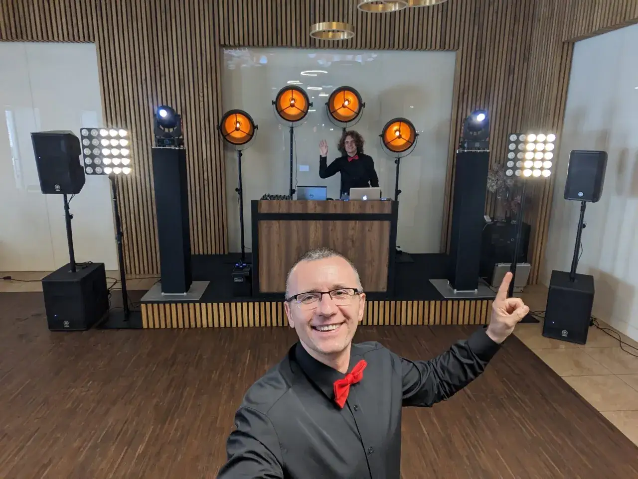 Uśmiechnięty DJ w muszce, gotowy do zabawy. Zastanawiasz się, ile kosztuje dj na imprezę? Sprawdź, jak stworzyć niezapomnianą atmosferę!