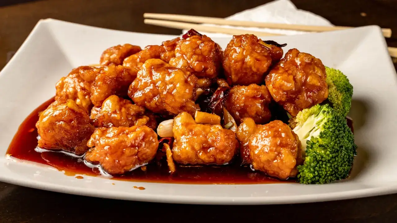 Azjatycki kurczak generała Tso w zdrowej wersji z pieca, oblany słodko-kwaśnym sosem, z dodatkiem brokułów.