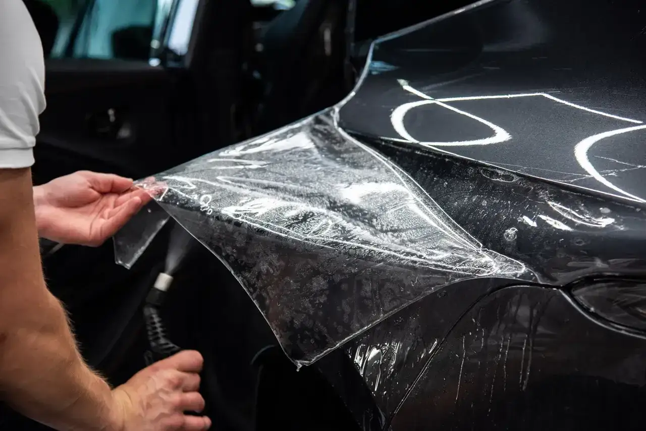 Nakładanie folii ochronnej na maskę samochodu. Zastanawiasz się, ile kosztuje pomalowanie maski w samochodzie? To może być alternatywa.