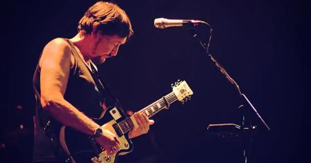 Chris Rea nie żyje. Muzyk gra na gitarze podczas koncertu, światła sceniczne podkreślają jego sylwetkę.