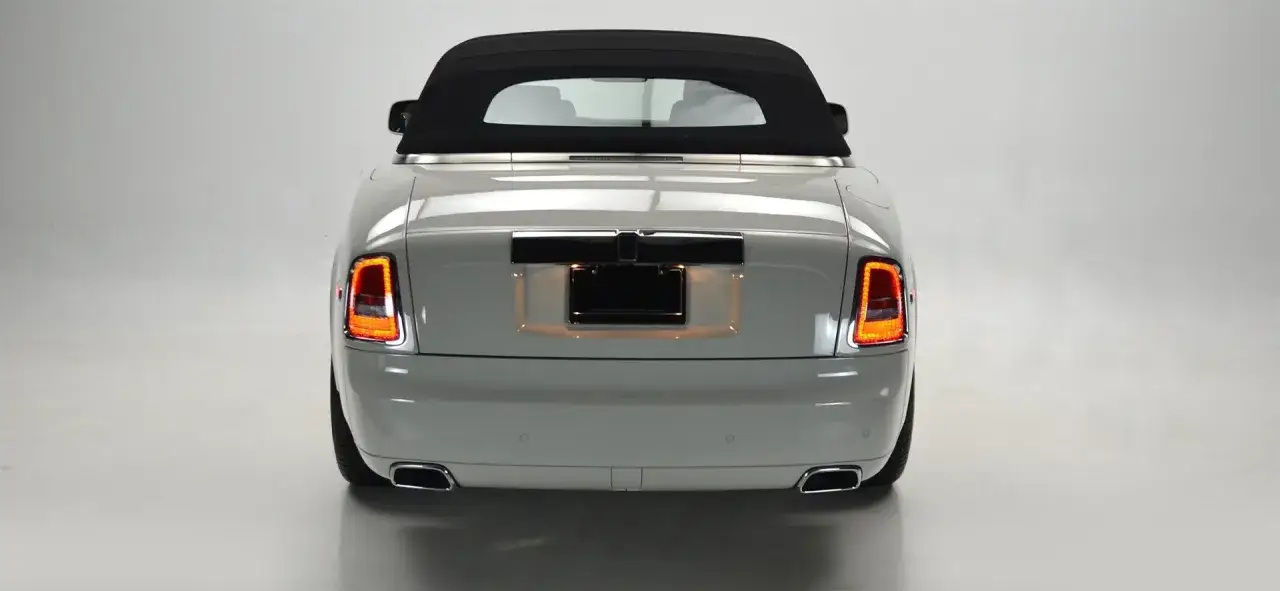 Tył luksusowego Rolls-Royce Phantom Drophead Coupe w kolorze jasnoszarym, z czarnym dachem i chromowanymi detalami.