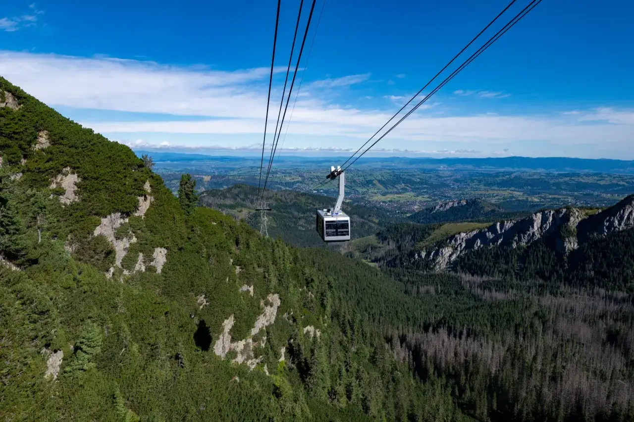 Kolejka linowa PKL Kasprowy Wierch wznosi się nad gęstym lasem i skalistymi zboczami Tatr.