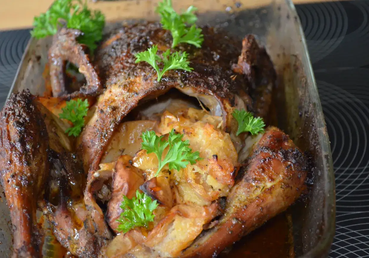 Pieczona kaczka w szklanym naczyniu, z aromatyczną marynatą do kaczki, udekorowana natką pietruszki.