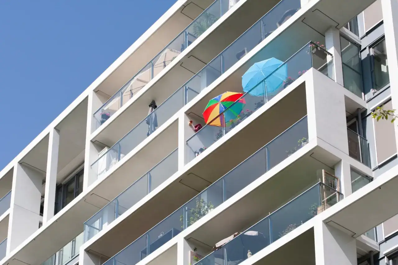 Kolorowe parasolki na balkonach w bloku, chroniące przed słońcem.