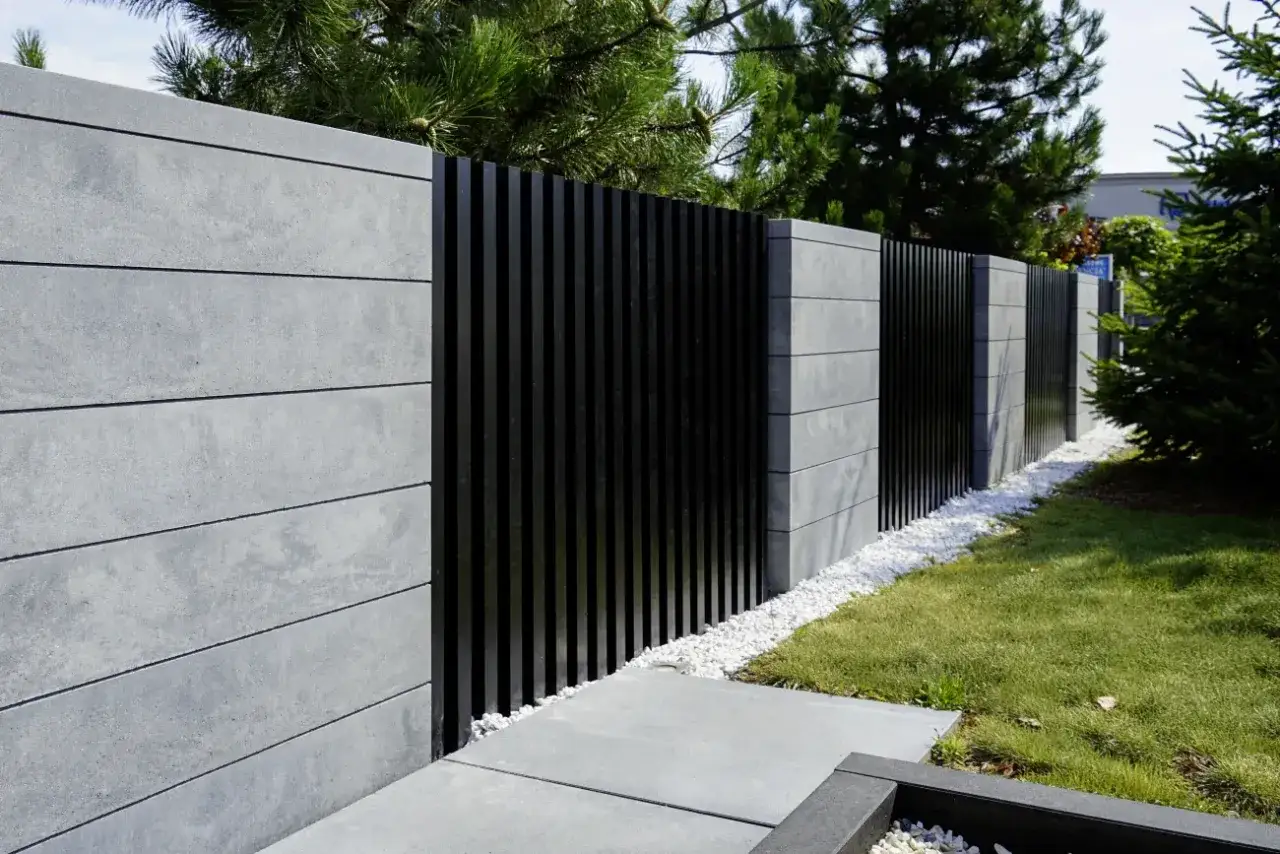 Nowoczesne ogrodzenie z betonowych płyt i czarnych paneli. Zastanawiasz się, ile kosztuje ogrodzenie działki?