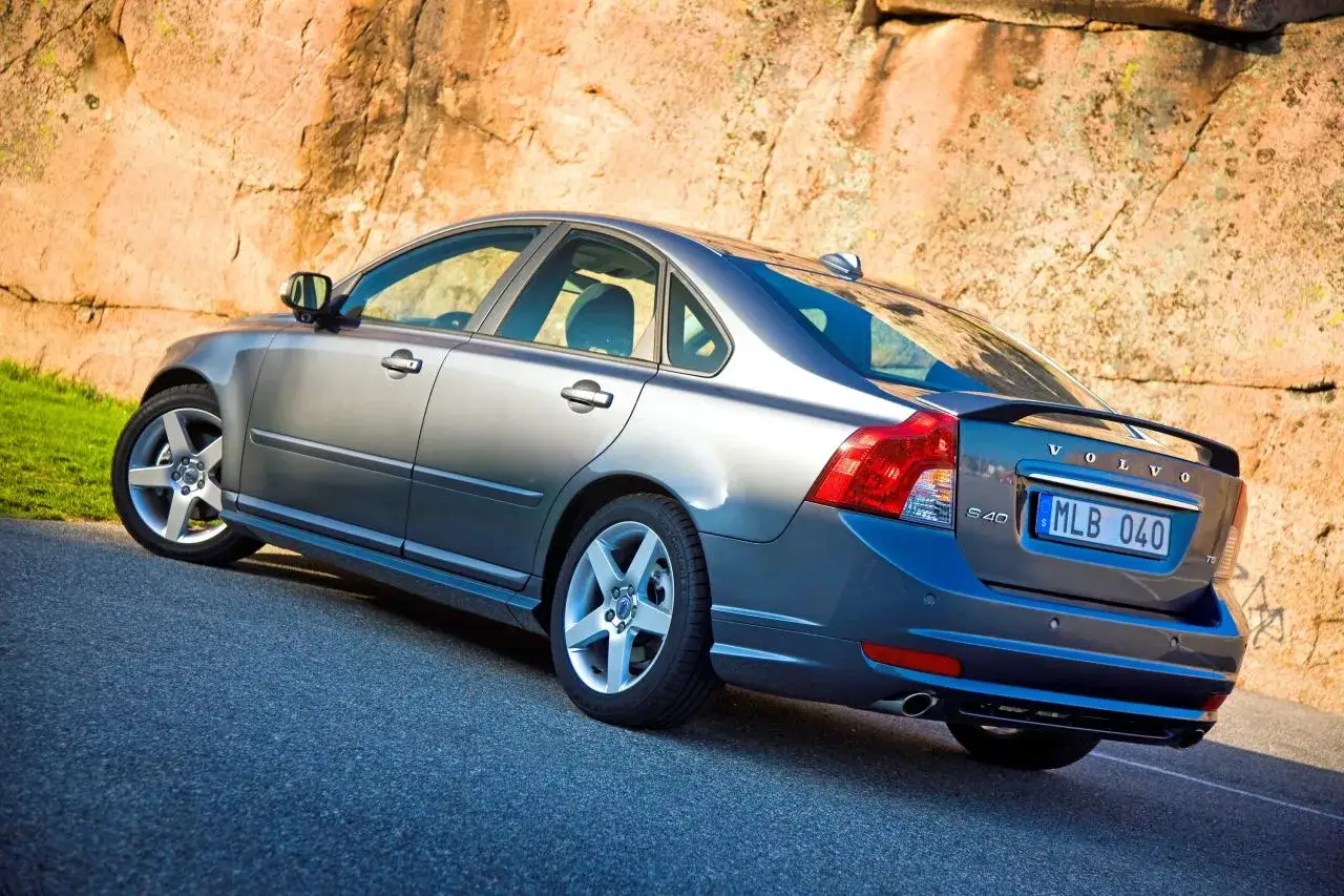 Szary sedan Volvo S40 zaparkowany przy skalnej ścianie. Jego wymiary są idealne do miasta i na dalsze trasy.