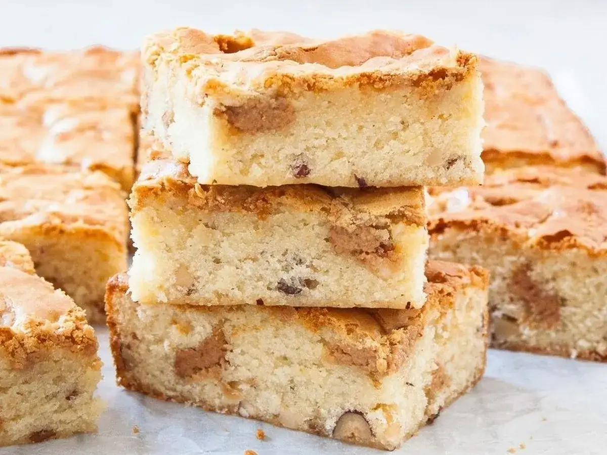 Słodkie brownie i blondie, ułożone w stosik, kuszą kawałkami orzechów i czekolady.