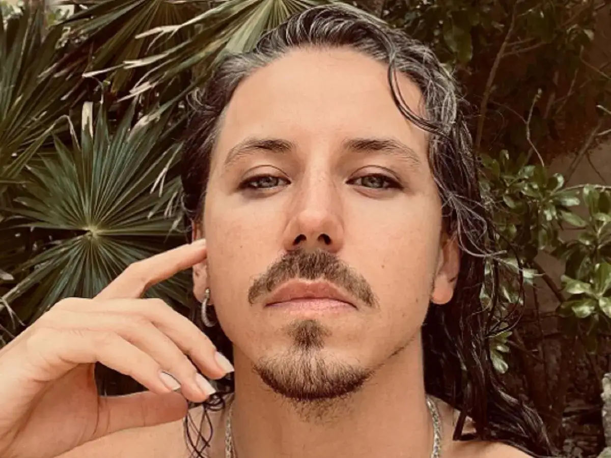Michał Szpak z dłonią przy uchu, w otoczeniu zieleni. Czy Michał Szpak ma żonę? To pytanie nurtuje fanów.