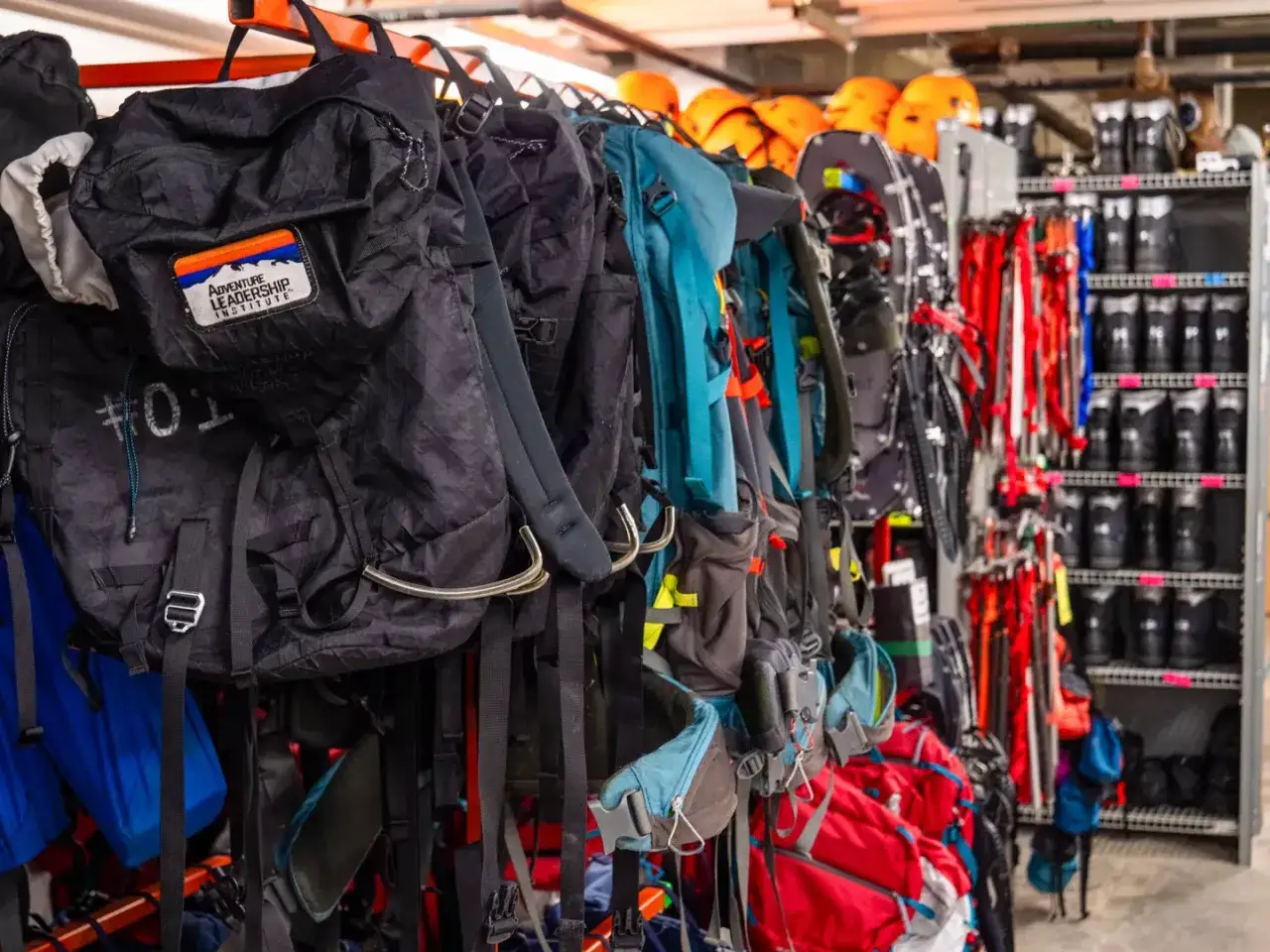 Rzędy plecak&oacute;w i sprzętu, gotowe na przygodę. Wiele gadżet&oacute;w pod namiot czeka na wyprawę.